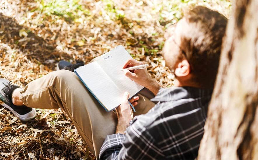 Man writing under tree